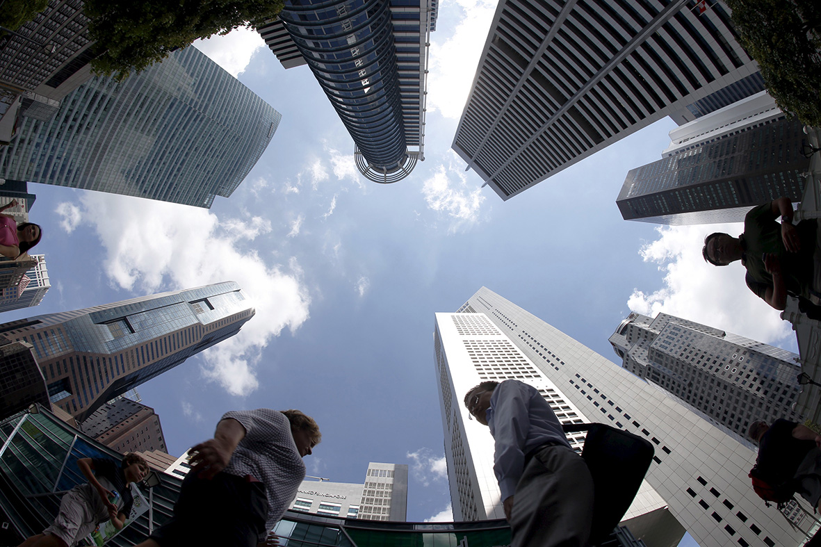 People walk past office buildings at the central business district in Singapore April 14