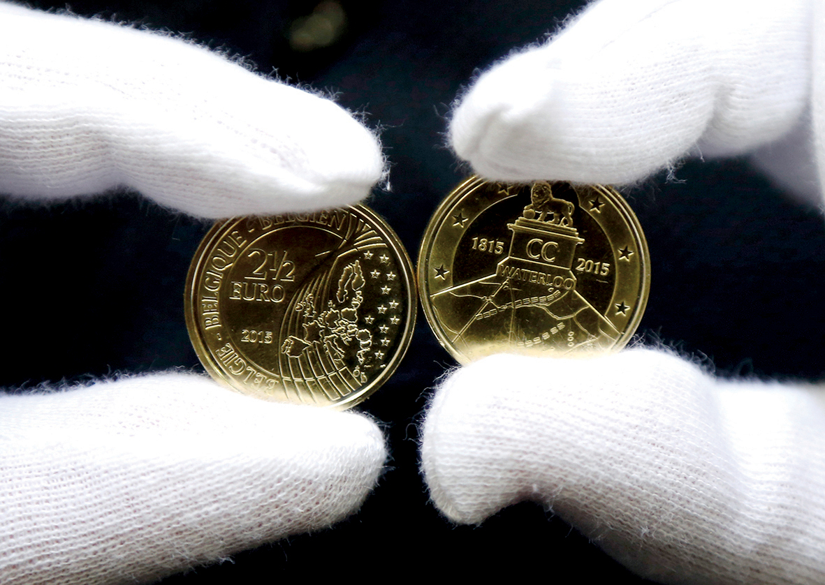 A worker displays newly minted commemorative 2.5 euro coins to mark the bicentennial of the battle of Waterloo