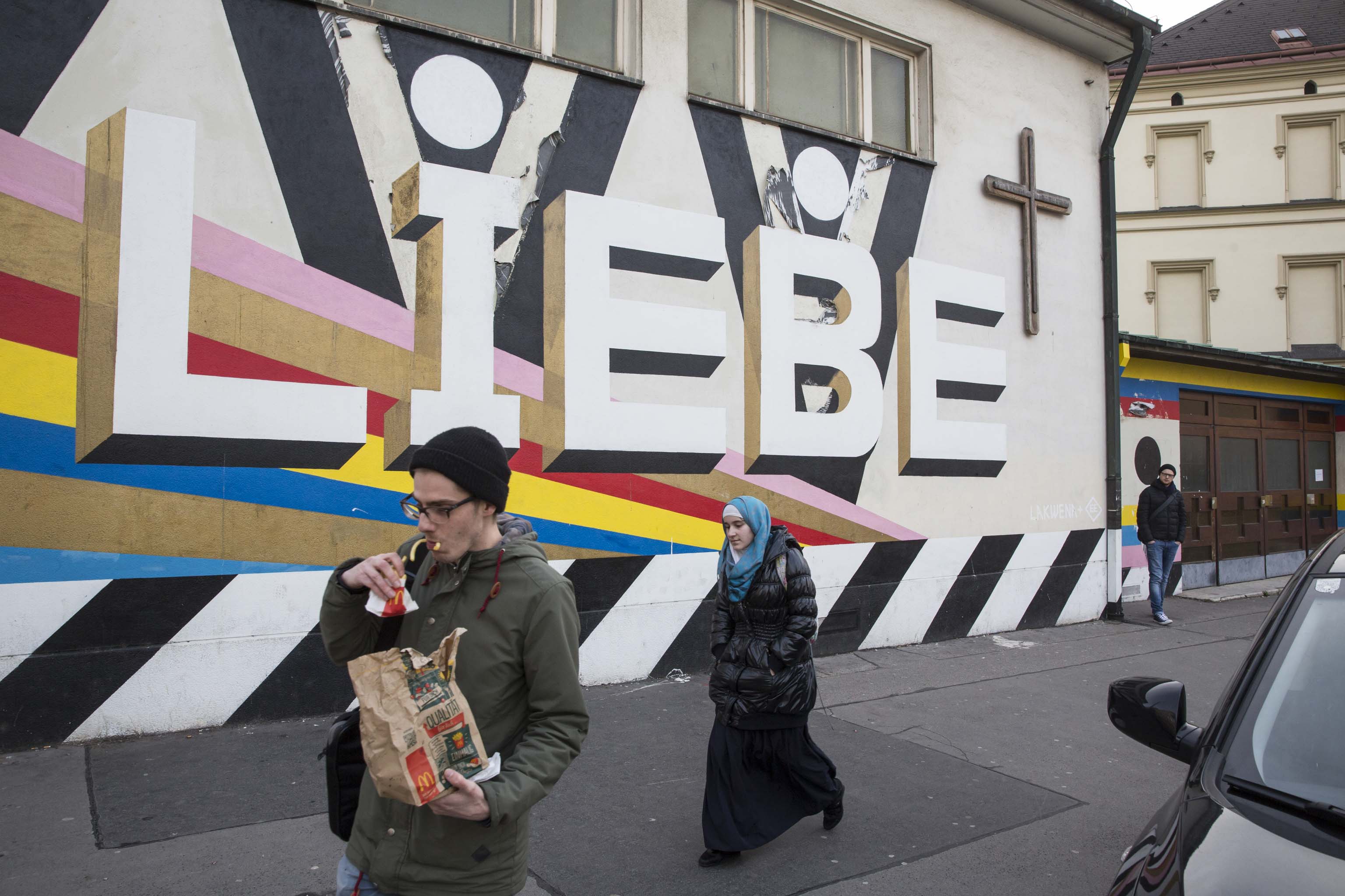 Stěna kostelu na rohu ulice Quellenstrasse a Gelertgasse hlásající pomocí graffiti lásku k bližnímu