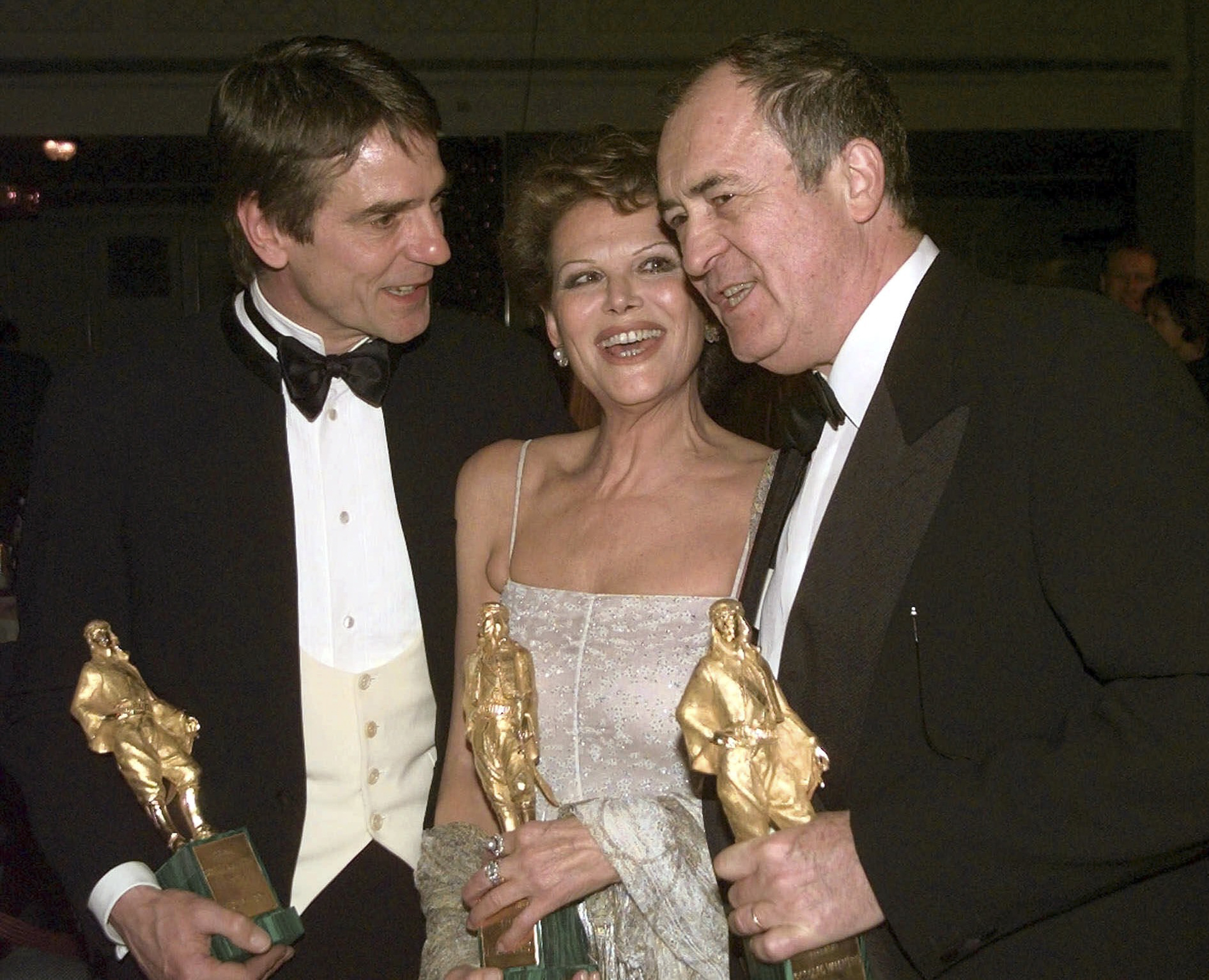 FILE - In this Feb. 24, 1999 file photo Italian actress Claudia Cardinale, center, British actor Jeremy Irons, left, and Italian director Bernardo Bertolucci hold their Rudolf Valentino awards they received during a ceremony in central London. Bertolucci, who won Oscars with "The Last Emperor" and whose erotic drama "Last Tango in Paris" enthralled and shocked the world, has died at the age of 77. Bertolucci's press office, Punto e Virgola, confirmed the death Monday, Nov. 26, 2018, in an email to The Associated Press. (AP Photo/Max Nash)