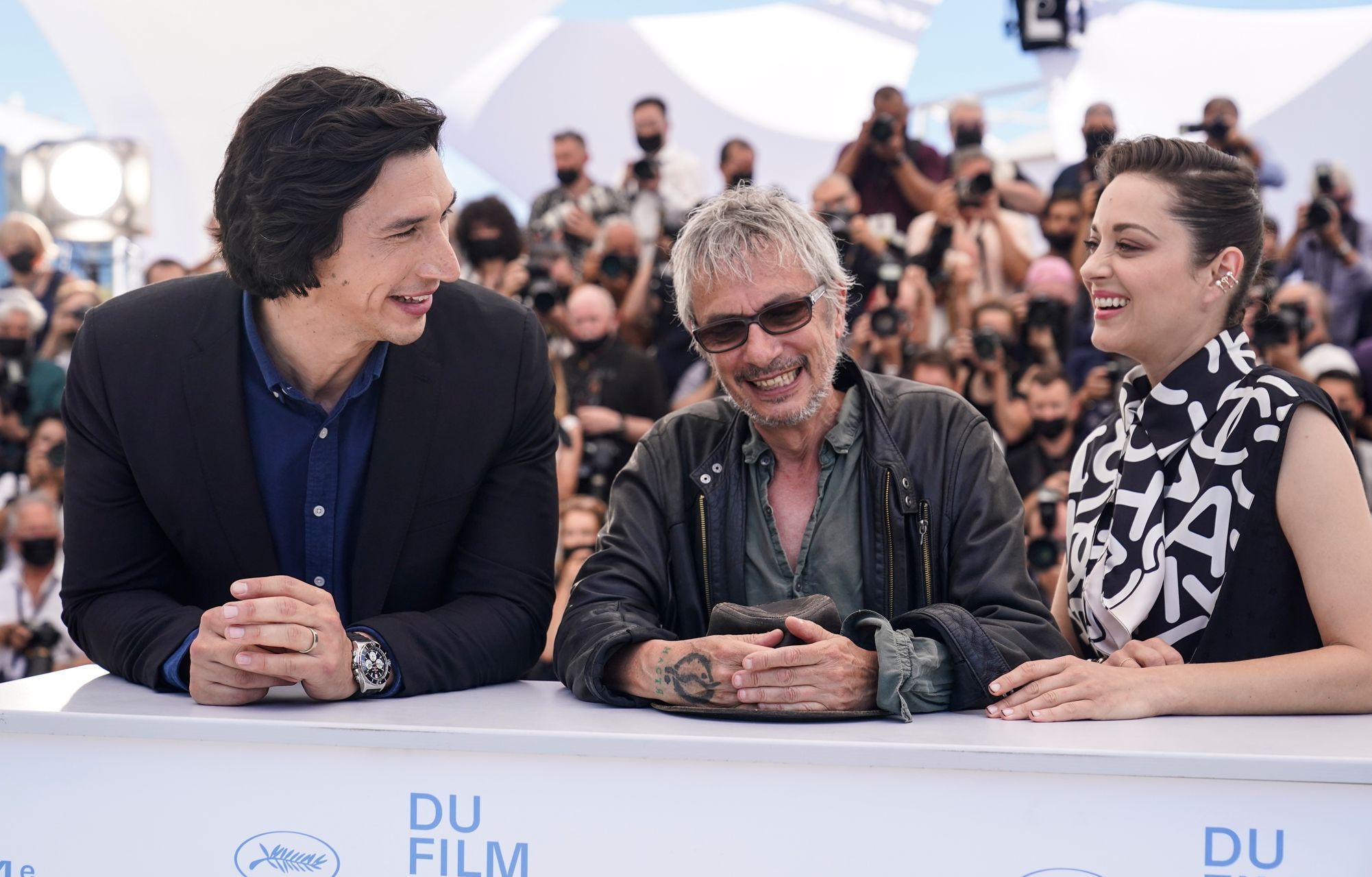 Herci Adam Driver a Marion Cotillard s režisérem Leosem Caraxem v Cannes