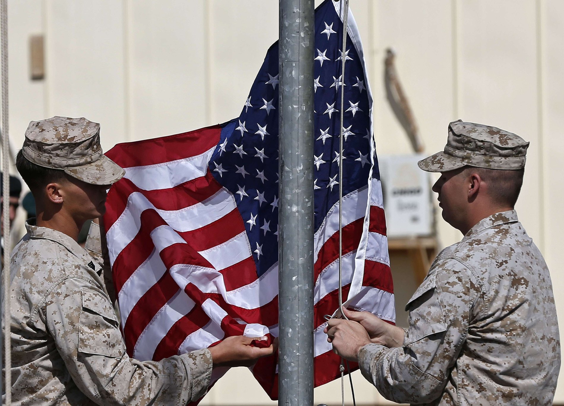 Američtí vojáci sundávají vlajku během ceremonie k ukončení své mise v Afghánistánu.