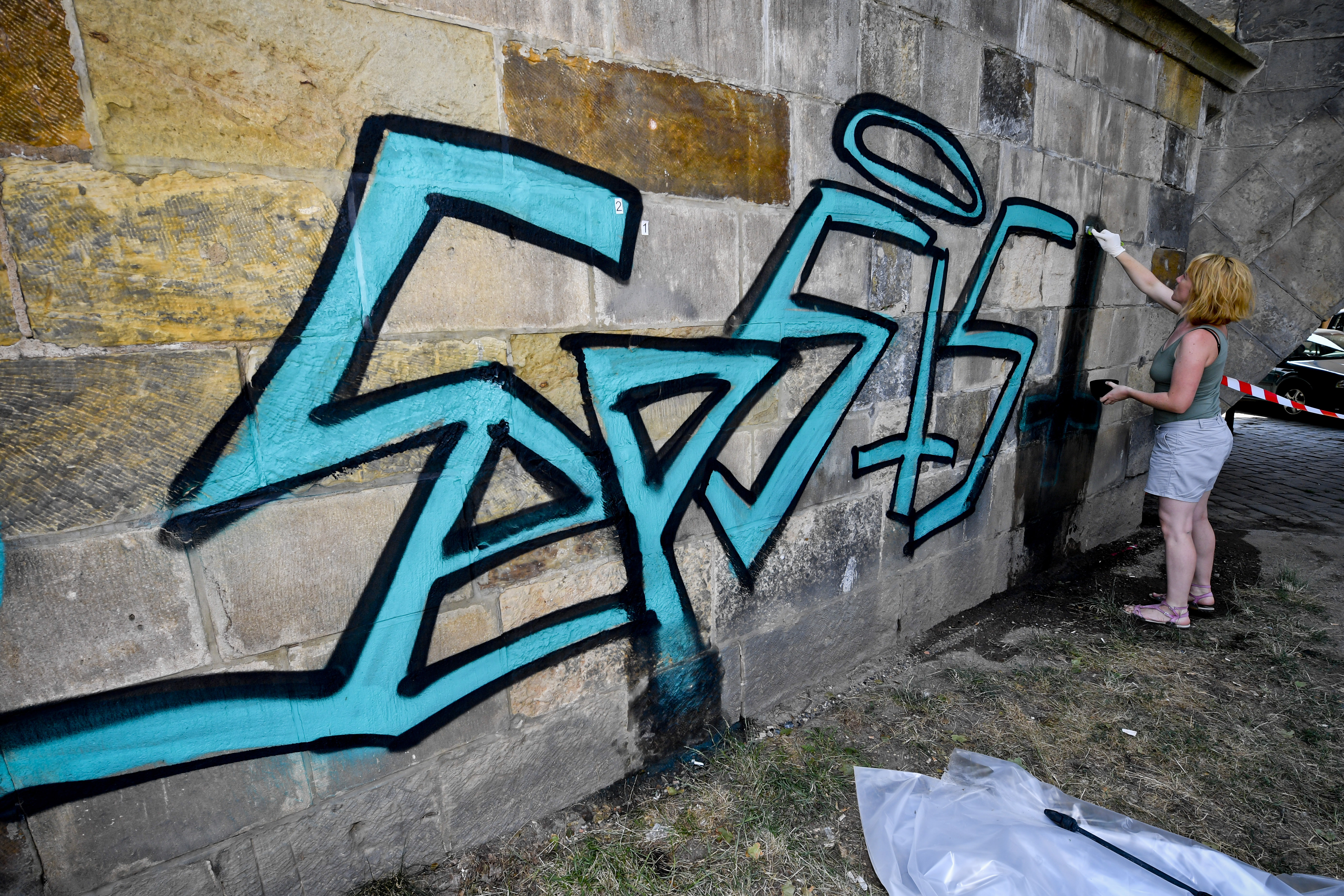 Restaurátoři začali 27. července 2019 pracovat na odstranění graffiti z pilíře Karlova mostu v Praze