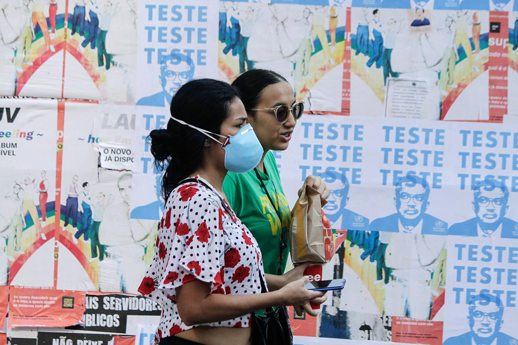 Brazilky procházejí okolo plakátu se šéfem WHO, který je vyzývá k testování