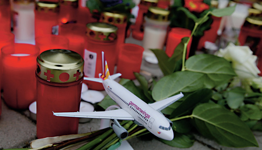 A model of a Germanwings plane is placed among flowers and lit candles in Cologne Bonn airport