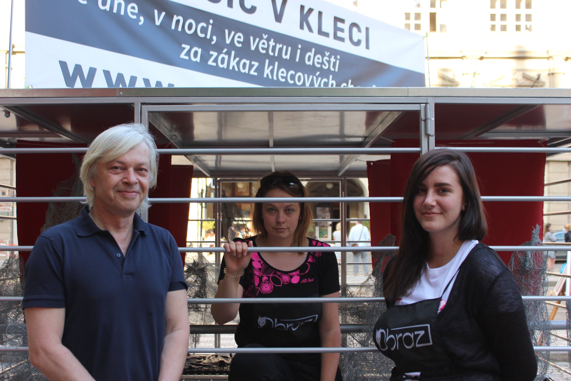 Lezu do klece, usedám na bidýlko mezi drátěné makety slepic, vmáčnutá mezi ně se nechávám fotit. 